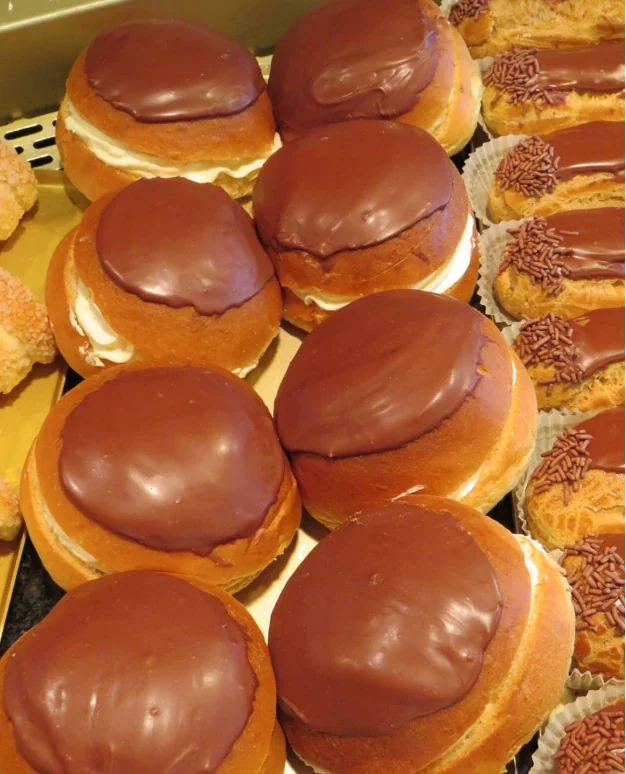 Gebakbollen met chocoladeglazuur en room, naast eclairs met chocolade en hagelslag