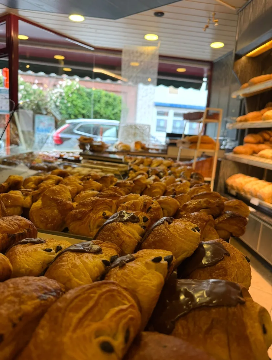 Binnenkant van de winkel met chocoladecroissants en koffiekoeken op de toonbank en broden op de planken