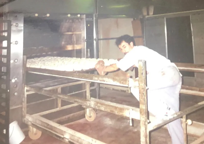 Oude foto: een bakker legt deegbolletjes klaar aan de oven