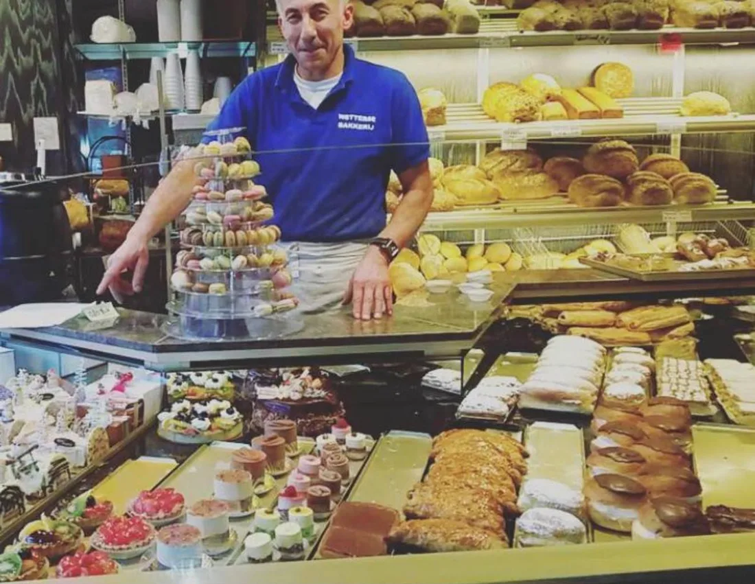 Mahmut achter de toonbank van de Wetterse Bakkerij, met gebak en brood in de vitrine
